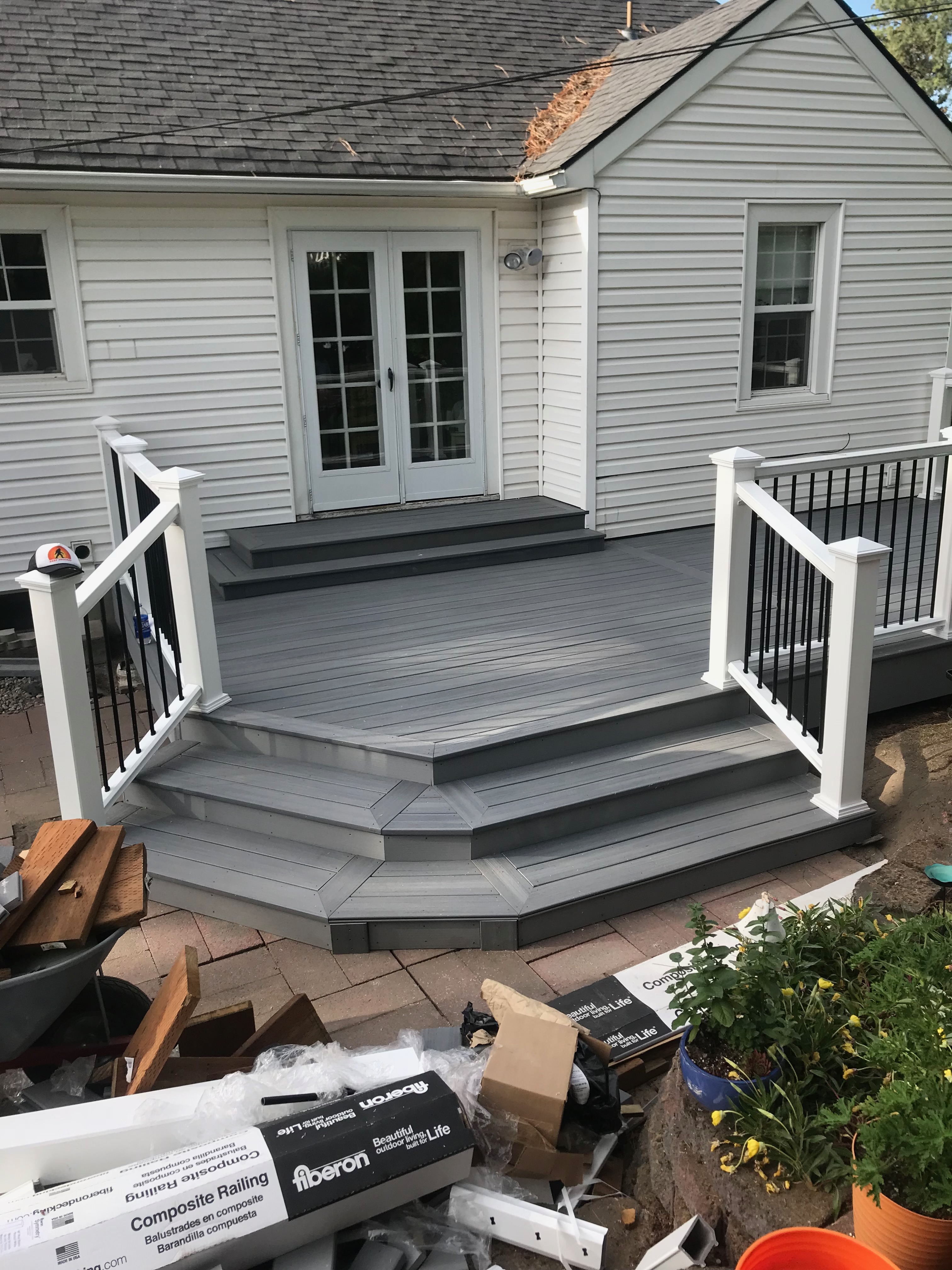 Grey composite deck with white and black railing system and terraced steps leading to the backyard.
