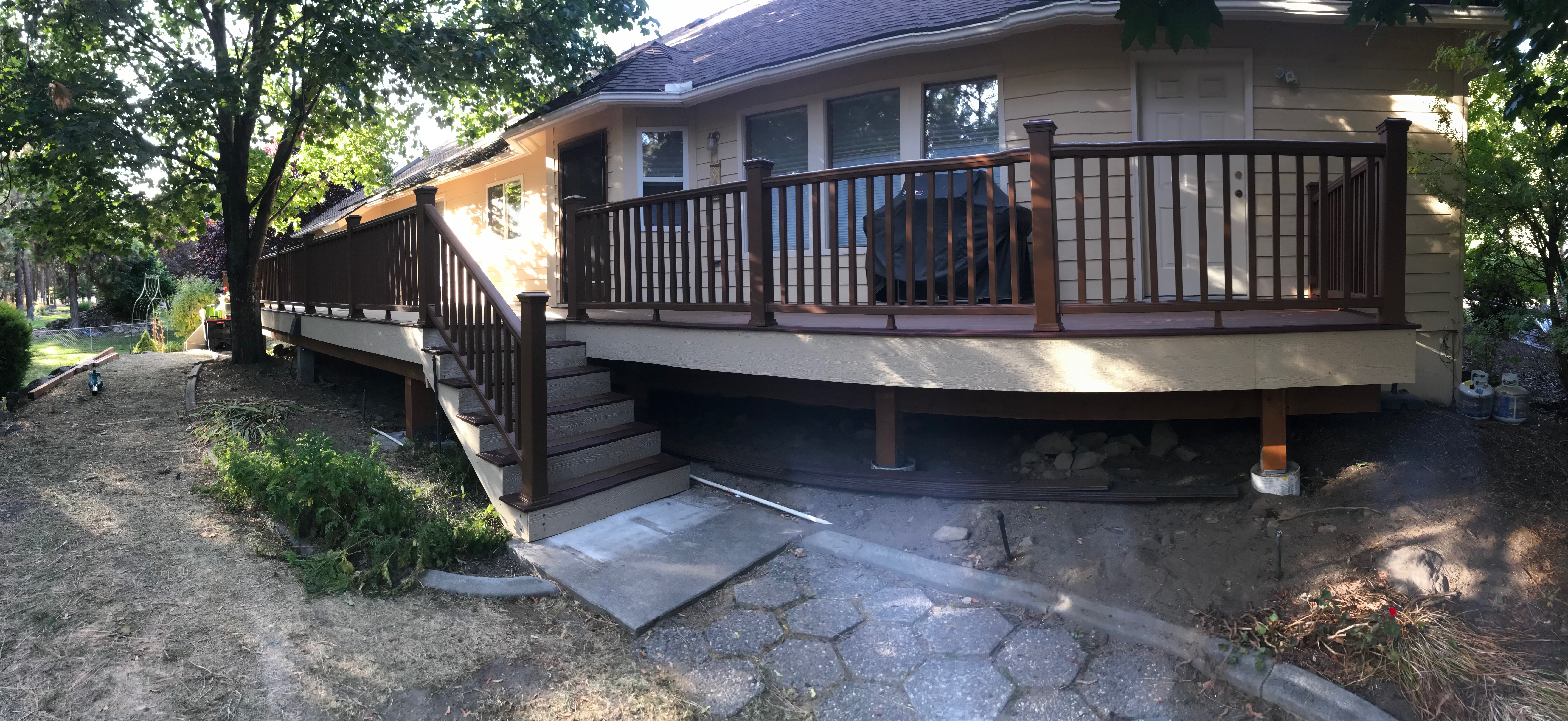 Panoramic view of composite deck with wood railing wrapping along the back of a home.